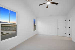 Unfurnished room with vaulted ceiling, light colored carpet, and a ceiling fan