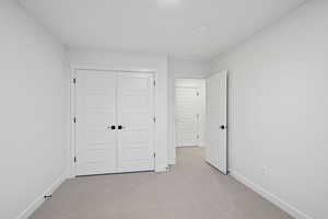 Unfurnished bedroom featuring light colored carpet and a closet