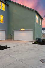 Property exterior at dusk with stucco siding, a garage, and concrete driveway
