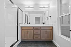 Full bathroom featuring a stall shower, double vanity, a textured ceiling, and dark tile patterned floors