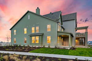 Back of property featuring stucco siding, roof with shingles, a chimney, and a lawn