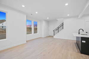 Unfurnished living room with light wood finished floors, stairway, and recessed lighting