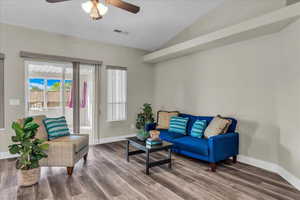 Living area featuring lofted ceiling, wood finished floors, and ceiling fan