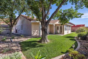 Rear view of house featuring french doors, stucco siding, and a tiled roof