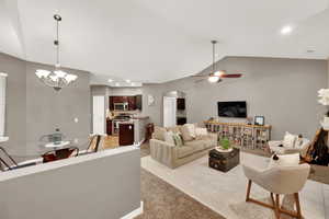 Living room with vaulted ceiling, arched walkways, recessed lighting, a chandelier, and ceiling fan