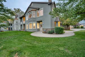 Rear view of property featuring stucco siding, a lawn, and stone siding