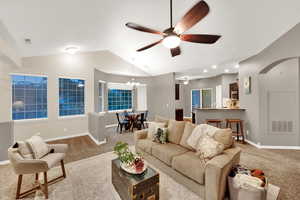 Carpeted living room with a ceiling fan, lofted ceiling, and a chandelier