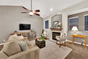 Living area with a glass covered fireplace, carpet flooring, lofted ceiling, ceiling fan, and recessed lighting