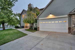 View of front facade featuring stone siding, stucco siding, concrete driveway, a front lawn, and a garage