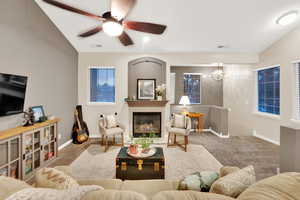 Carpeted living area featuring a fireplace, a ceiling fan, and lofted ceiling