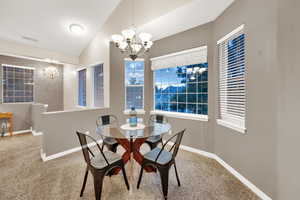 Dining space featuring a chandelier, carpet floors, and lofted ceiling