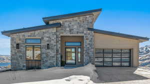 View of front facade featuring stone siding, a mountain view, a garage, and board and batten siding