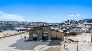 View of front of home with a mountain view, stone siding, an attached garage, concrete driveway, and solar panels