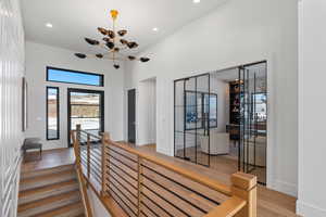 Hallway featuring light wood-type flooring, an upstairs landing, recessed lighting, a chandelier, and a high ceiling