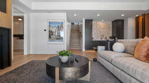 Living room with stairway, light wood-type flooring, and recessed lighting