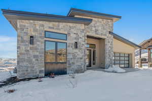 Contemporary home with stone siding, an attached garage, and a mountain view