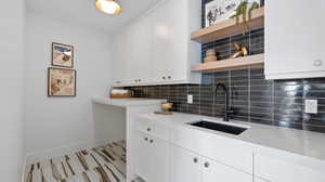 Kitchen featuring open shelves, tasteful backsplash, white cabinetry, and light stone countertops