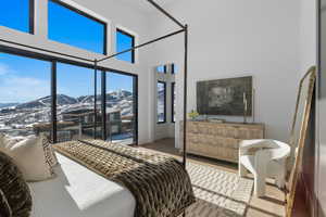 Bedroom featuring a towering ceiling, wood finished floors, access to exterior, and a mountain view