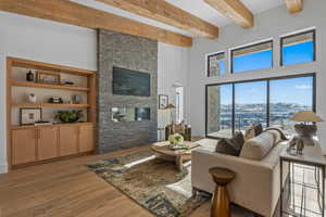 Living area featuring a towering ceiling, light wood finished floors, beam ceiling, and a mountain view
