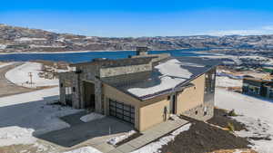 View of front of house featuring a mountain view, stone siding, a chimney, driveway, and an attached garage