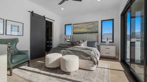 Bedroom featuring a barn door, light wood-type flooring, multiple windows, a ceiling fan, and recessed lighting