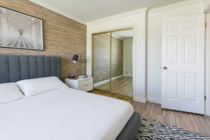 Bedroom with light wood-style flooring, a closet, and ornamental molding