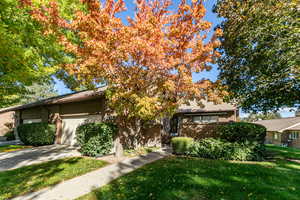 View of front facade with brick siding, a front lawn, an attached garage, and driveway