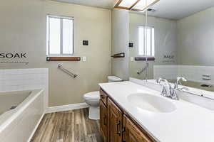 Full bath with a garden tub, dark wood-type flooring, and vanity