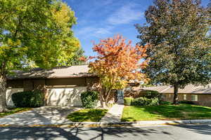 View of front facade featuring brick siding, driveway, a gate, a shingled roof, and a garage