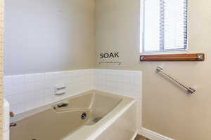 Bathroom featuring wallpapered walls and a jetted tub