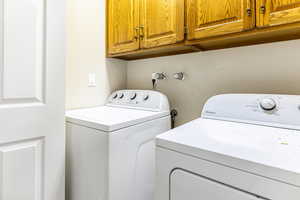 Washroom with washer and clothes dryer and cabinet space