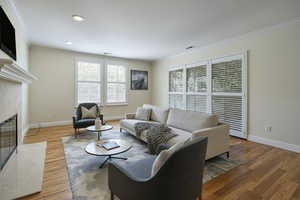 Living room featuring crown molding, wood finished floors, a premium fireplace, and recessed lighting