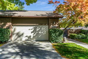 View of side of home with brick siding, driveway, and a shingled roof