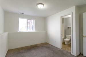 Unfurnished bedroom featuring light colored carpet and ensuite bath