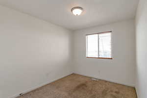 Spare room featuring light carpet and baseboards