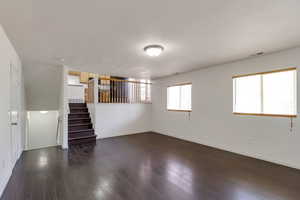 Unfurnished living room with dark wood finished floors and stairs