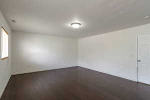 Spare room featuring dark wood-type flooring and baseboards