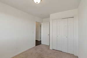 Unfurnished bedroom featuring light carpet and a closet