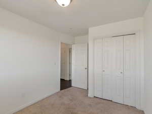 Unfurnished bedroom featuring light carpet and a closet