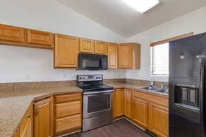 Kitchen featuring black appliances, lofted ceiling, and dark wood-style flooring
