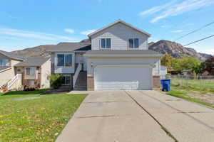 Split level home with a mountain view, driveway, a garage, and brick siding