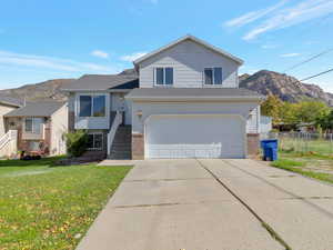 Split level home with a mountain view, driveway, a garage, and brick siding