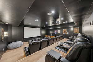 Home theater room featuring light wood-type flooring, recessed lighting, and a tray ceiling