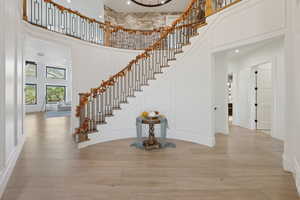Stairs with wood finished floors, a towering ceiling, and recessed lighting