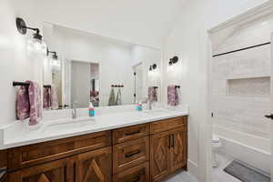 Bathroom with double vanity, light tile patterned floors, and shower / washtub combination