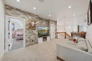 Living area with carpet, recessed lighting, and a warm lit fireplace