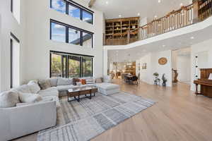 Living area with light wood finished floors, recessed lighting, stairway, and a towering ceiling