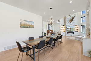 Dining room featuring light wood-type flooring, a fireplace, recessed lighting, and a chandelier