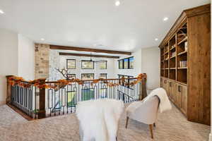 Living area featuring an upstairs landing, beam ceiling, recessed lighting, and ceiling fan