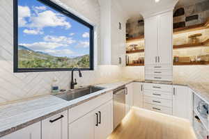 Kitchen featuring open shelves, white cabinetry, light stone countertops, backsplash, and a mountain view